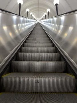 Low angle vertical photo of long metal escalator in grey metallic design. Alo Stock Photos