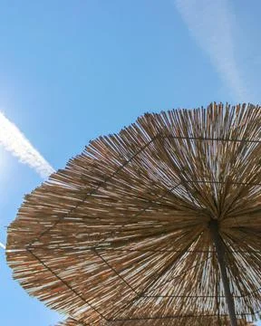 Low angle vertical view of straw beach umbrella against clear blue sky 스톡 사진