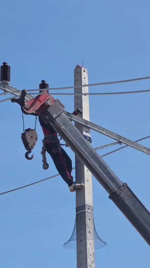 Low angle video of a skilled lineman in a safety harness on a concrete pole. Stock-Footage 338298511