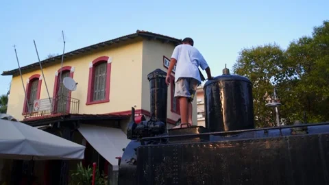 Low angle view of 10 years old caucasian boy standing on the engine of a Stock Footage 280259102