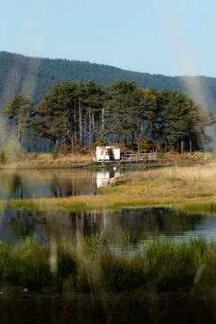 Low angle view of a abandoned white van on an island in a lake. Stock Photos