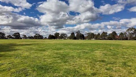 Low-angle view across an open grassy sports field in suburban Australia. Stock Footage 316796960
