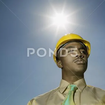 Low angle view of African American man wearing hard hat Stock Photos