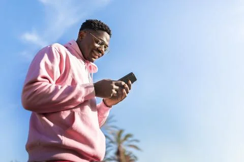 Low angle view of African American man using smart phone outdoors. Copy space Stock Photos