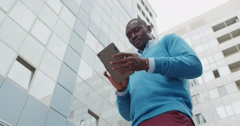 Low angle view of afro-american businessman using digital tablet outdoors Stock Footage 157905597
