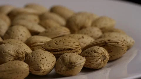 Low angle view of almonds rotating on white plate Stock Footage 328144134