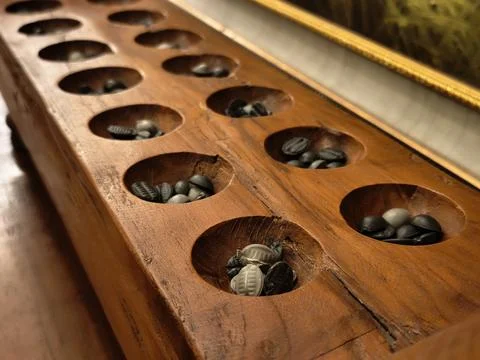 Low angle view along the row of holes on a wooden congklak board Stock Photos