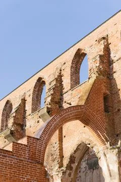 A low-angle view of ancient brick ruins with Gothic arches against a clear blue Stock Photos