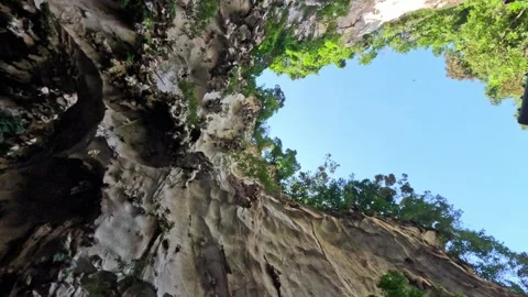 Low-angle view of ancient rocky cliffs with trees and blue sky Video stock 339926007