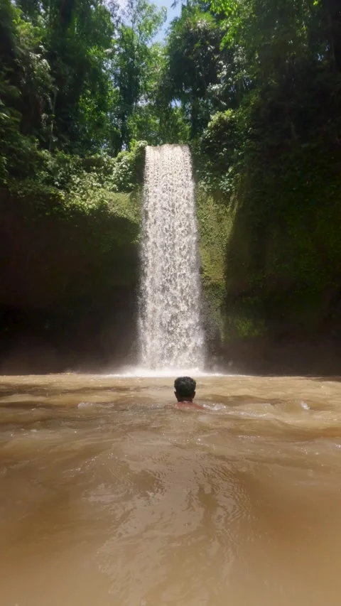 Low-Angle view of Asian man in plunge pool, swimming towards hidden waterfall Stock Footage 328712777