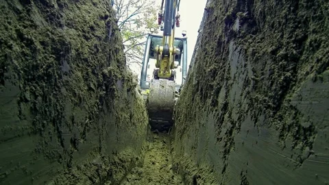 Low Angle View of a Backhoe Digging a Trench Stock Footage 310936726