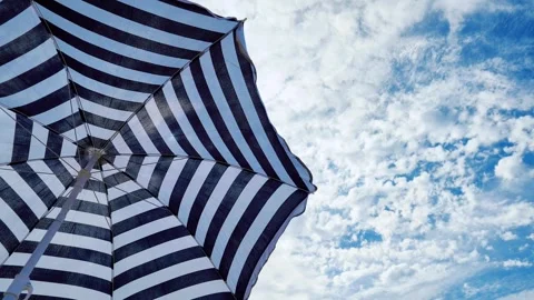 Low-angle view of a beach umbrella shielding tourists from the hot sun. Stock Footage 337349789