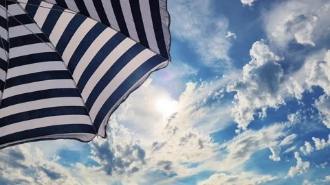 Low-angle view of a beach umbrella shielding tourists from the hot sun. Stock Footage 337349790