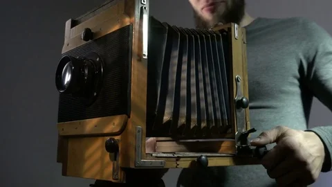Low angle view of bearded photographer adjusting old vintage wooden photo camera Stock Footage 75923225