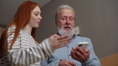 Low-angle view of bearded senior grandfather learning to using mobile phone Video stock 166156568