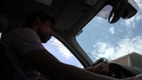 Low angle view from below of the passenger seat of a man driving a car in the da 库存影片 197078661