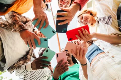 Low angle view of a big group of smiling multiracial teenagers addicted to smart Stock Photos