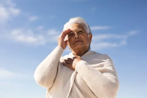 Low angle view of biracial senior woman shielding eyes while looking away Stock Photos