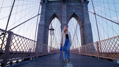 Low-angle view of a blonde-haired female tourist running along iconic landmark Video stock 202225437