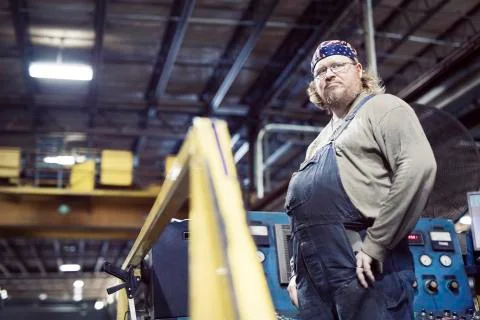Low angle view of blue collar worker wearing bib overalls and headscarf while Fotos de archivo