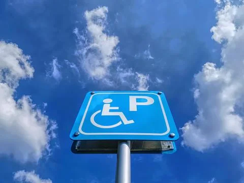 Low Angle View of Blue Handicapped Parking Sign Against Blue Cloudy Sky at Da Foto stock
