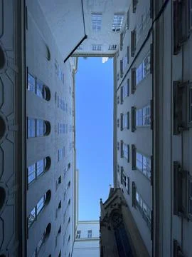 Low angle view of blue sky seen in the gap of high residential building. Abst Stock Photos