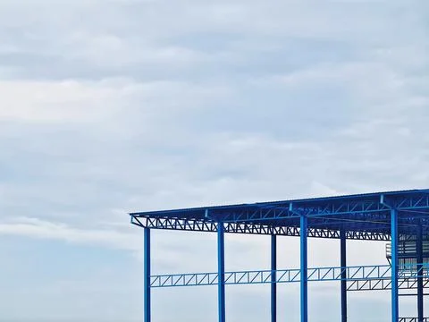 Low Angle View of Blue Warehouse Structure Against Cloudy Sky Foto stock