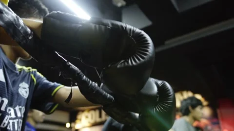 Low Angle View of Boxer Resting Boxing Gloves on Ring Ropes During Training 動画素材 339103234