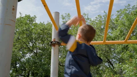 Low Angle View of Boy Climbing Monkey Bars Under Blue Sky Stock Footage 328635155