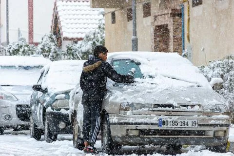 Low angle view of a boy removing the snow from a car window. Stock Photos