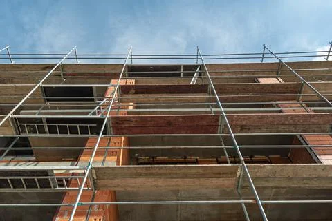 Low angle view of brick building renovation with metal scaffolding and wooden Stock Photos