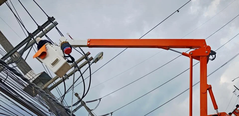 Low angle view of bright orange boom arm of bucket truck lifting lineman . Stock Photos