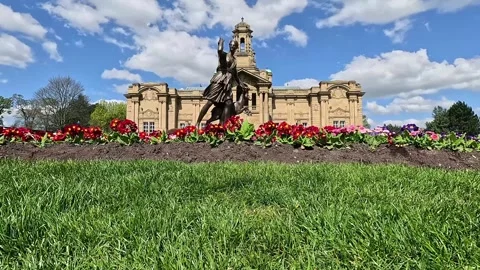 Low angle view of a bronze statue and Cartwright Hall in Lister Park, Bradford Stock Footage 333794064