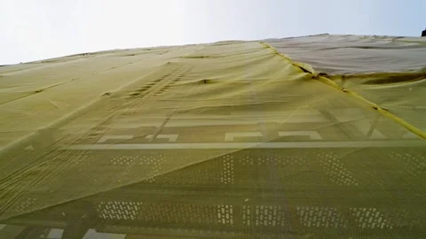 Low-angle view of a building facade wrapped in yellow safety mesh over Stock Footage 333650385