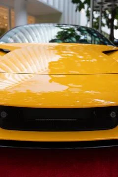 Low angle view on bumper of bright yellow vehicle with glossy windshield and Stock Photos