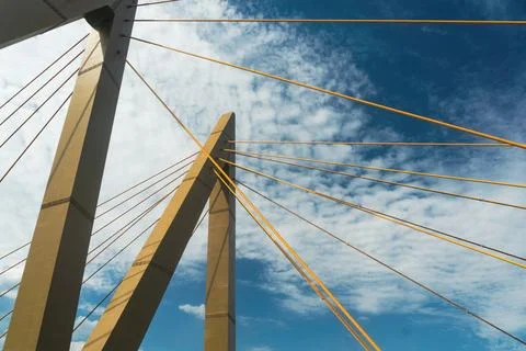 Low angle view of cable-stayed bridge with yellow cables against blue sky Stock Photos