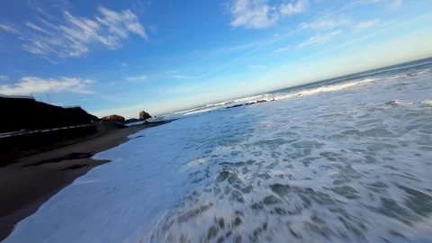 Low-angle view captures ocean waves splashing over wet sand Stock Footage 346158356