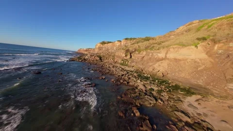 Low-angle view captures seafoam crashing near rugged coast Stock Footage 344559193