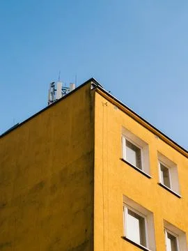Low angle view capturing a vibrant yellow building corner adorned with antennas Stock Photos