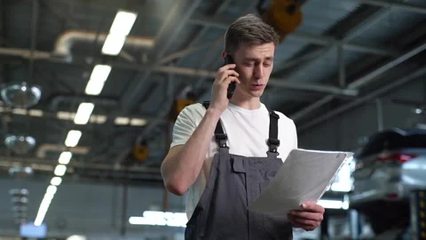 Low-angle view of cheerful auto mechanic male wearing uniform with clipboard Stock Footage 161956668