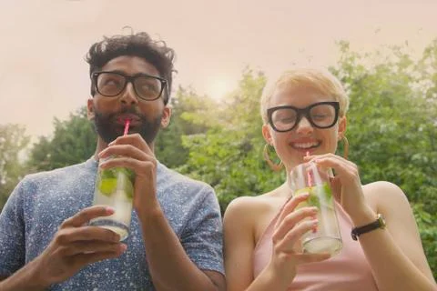 Low angle view of cheerful couple drinking lemonade at yard Stock Photos