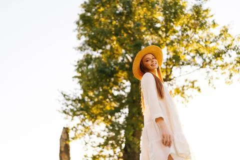 Low-angle view of cheerful young woman wearing straw hat and white dress Stock Photos