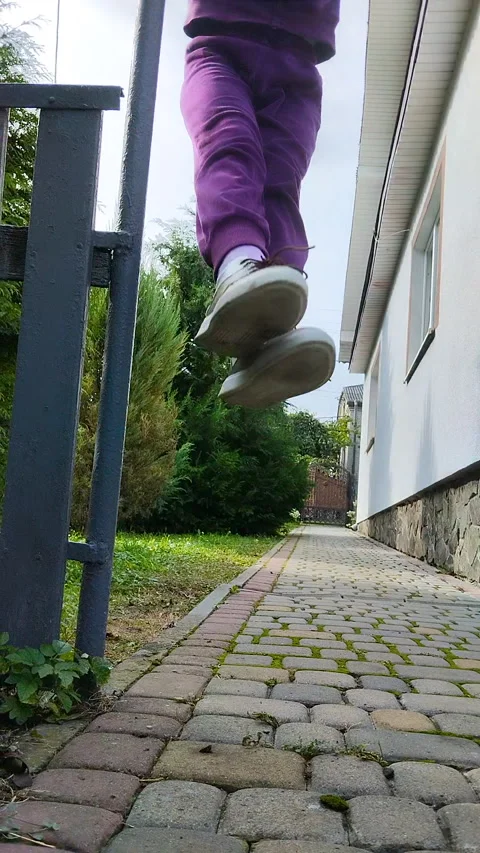 Low angle view of a child jumping or hanging on a playground outdoors Stock Footage 335450106