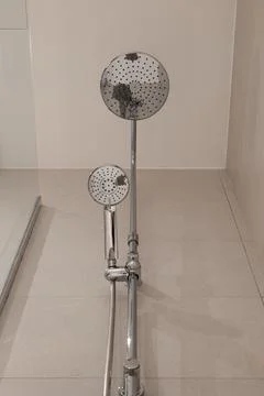Low angle view of chrome shower fixture with large rain shower head and handheld Stock Photos