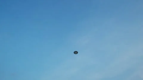 Low Angle View of a Circular UFO Flying Saucer Hovering in a Clear Blue Sky Stock Footage 334536995