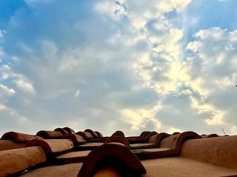 Low Angle View of Clay Roof Tiles Against Blue Sky with Clouds and Sunlight Stock Photos