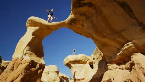 Low angle view of climbers balancing on scenic rock formations under clear blue 库存照片