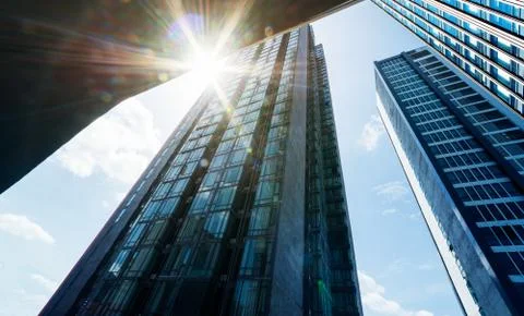 Low angle view of common modern business skyscrapers with sun flare . Stock Photos