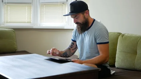 Low angle view of concentrated young man with stubble and curly hair sitting Video stock 98882700