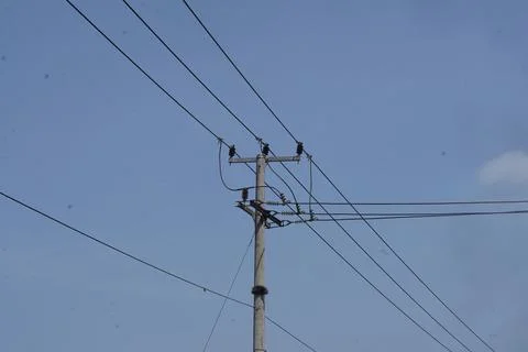 Low-angle view of a concrete utility pole with power transmission lines against Stock Photos